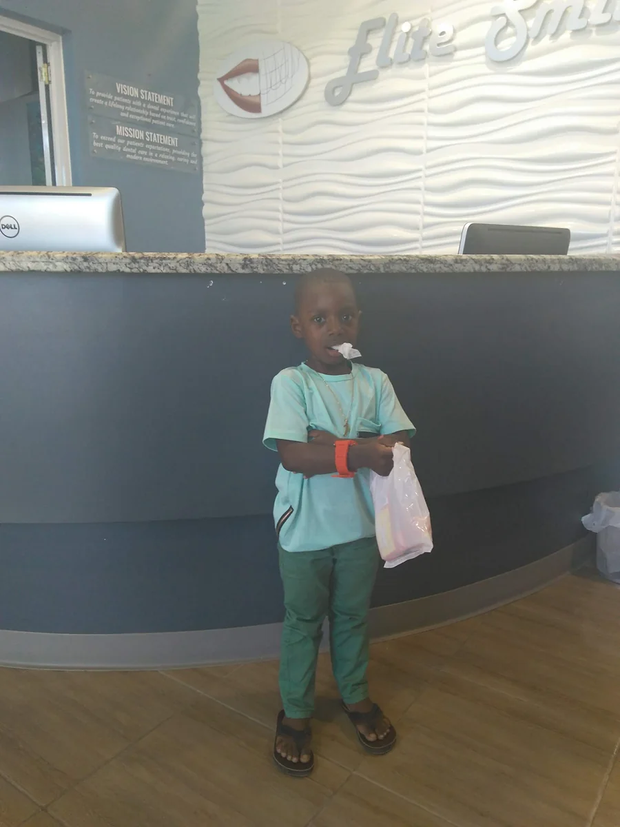 A young patient holding a take-home bag at the Elite Smiles reception desk