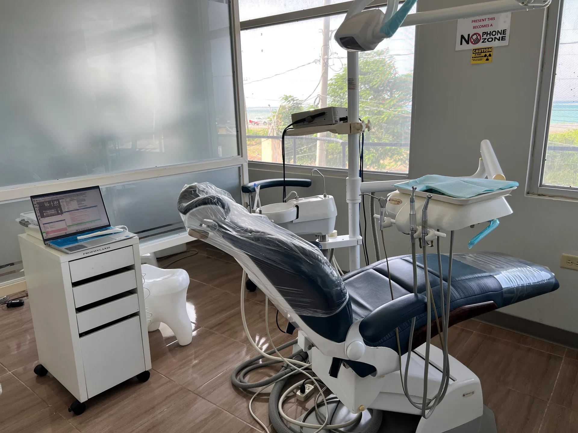 A sunlit Elite Smiles treatment room with a blue dental chair and large windows